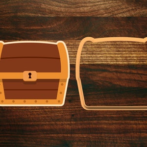 May include: A brown wooden treasure chest with a gold trim and a keyhole. The chest is on a wooden background. There is a cutout of the chest next to it.