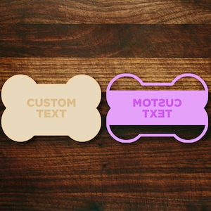 May include: Two dog bone-shaped tags, one beige and one purple. The beige tag says "CUSTOM TEXT" and the purple tag says "CUSTOM TEXT" in reverse.
