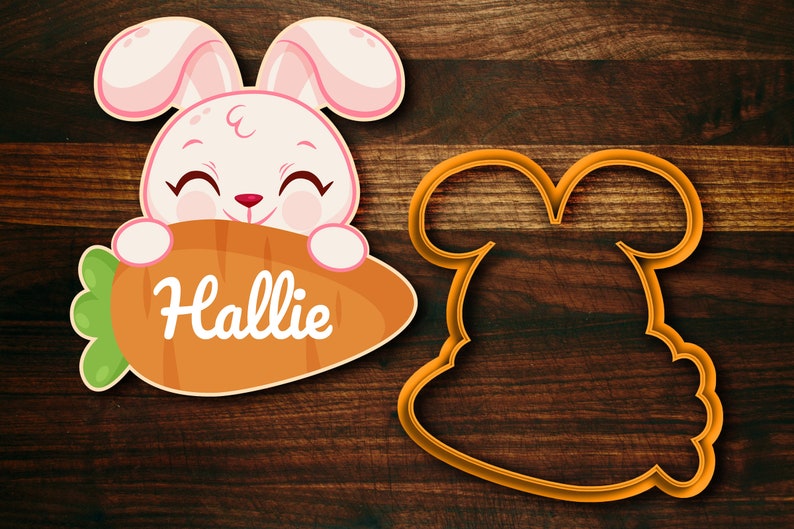 May include: A pink bunny rabbit cookie cutter with a carrot in its mouth. The carrot has the name "Hallie" written on it. There is also a blank bunny cookie cutter.
