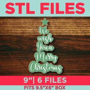 May include: A green Christmas tree design with the text "We wish You a Merry Christmas" in a script font. The image also includes the text "STL FILES" and "9" | 6 FILES". The design fits a 24.1cm x 15.2cm box.