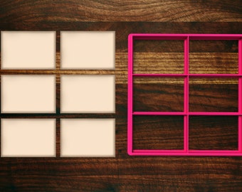 May include: A set of six blank square labels next to a pink plastic grid with six squares. The labels and grid are on a dark brown wooden surface.