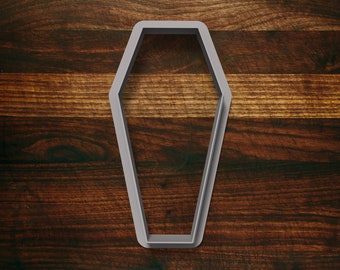 May include: A silver-colored metal cookie cutter in the shape of a coffin.