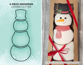 May include: A four-piece snowman cookie cutter set. The cutter is made of metal and is shaped like a snowman. The snowman has a hat, a scarf, and a carrot nose. The cutter is packaged in a brown box with a red ribbon.