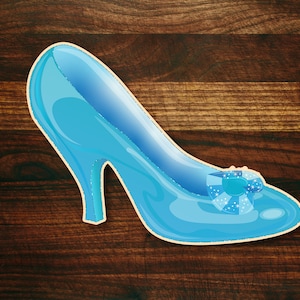 May include: A light blue glass slipper with a sparkly blue bow on the toe. The slipper is on a brown wooden background.