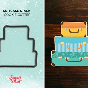 May include: A cookie cutter in the shape of a stack of three suitcases. The suitcases are in different colors and patterns. The top suitcase is yellow, the middle suitcase is blue with white stripes, and the bottom suitcase is green with a floral pattern. The cookie cutter is made of metal and has a smooth surface.