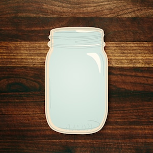 May include: A clear glass mason jar with a light blue interior. The jar is sitting on a dark brown wooden surface.