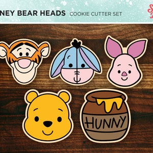 May include: Set of five cookie cutters featuring Winnie the Pooh characters: Tigger, Eeyore, Piglet, Winnie the Pooh, and a honey pot with the word "Hunny".