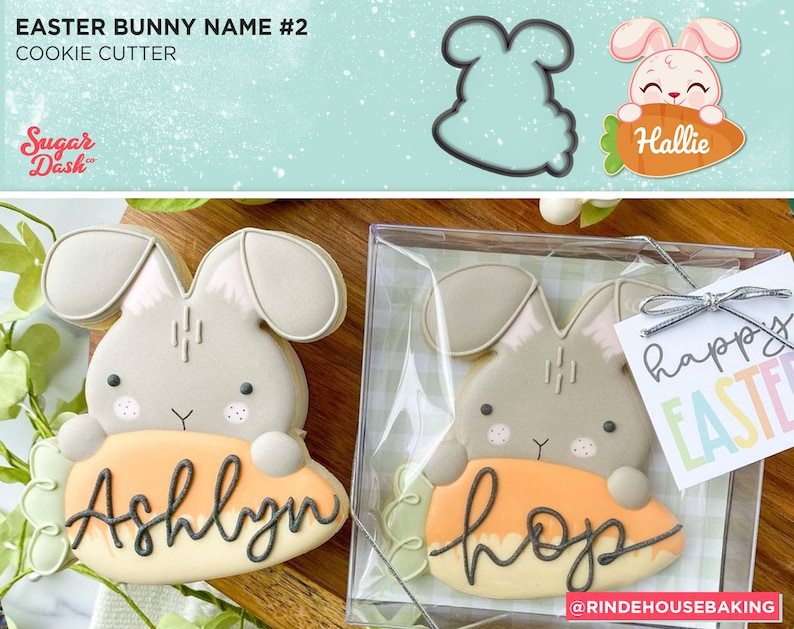 May include: Two decorated sugar cookies shaped like Easter bunnies holding carrots. The carrots are decorated with the names "Ashlyn" and "Hop". The cookies are in a clear plastic container with a tag that says "Happy Easter".