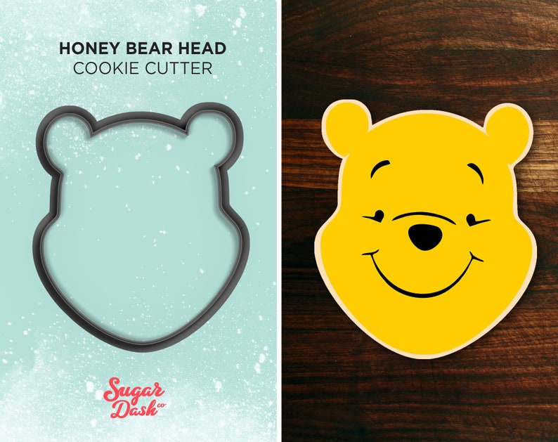 May include: A black cookie cutter shaped like Winnie the Pooh's head. The text "HONEY BEAR HEAD COOKIE CUTTER" is above the cutter. The text "Sugar Dash" is below the cutter.