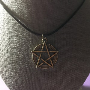 May include: A gold-toned pentagram pendant necklace with a black cord.