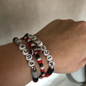 May include: Three beaded bracelets with the words "MICHIGAN", "F.U.C.K", and a football charm.