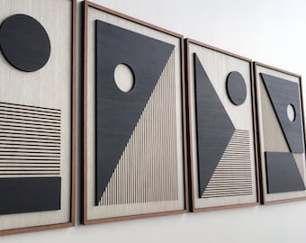 May include: Four framed abstract wall art pieces. Each piece features geometric shapes in black and beige, with a wooden frame. Designs include circles, triangles, and horizontal lines. The artwork is displayed on a white wall.