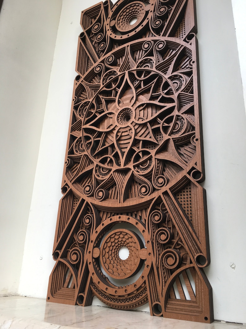 Puede incluir: Una pieza de arte de pared de madera con un dise&ntilde;o geom&eacute;trico intrincado. El dise&ntilde;o presenta un c&iacute;rculo central con un patr&oacute;n en espiral y est&aacute; rodeado de c&iacute;rculos y l&iacute;neas m&aacute;s peque&ntilde;os. La pieza est&aacute; hecha de m&uacute;ltiples capas de madera, creando un efecto 3D.