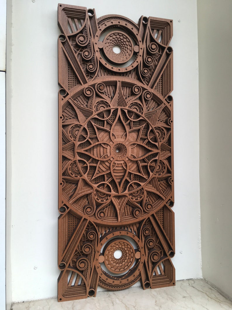 Puede incluir: Una pieza de arte de pared de madera con un dise&ntilde;o geom&eacute;trico que presenta detalles intrincados y un patr&oacute;n circular en el centro. La pieza est&aacute; hecha de madera marr&oacute;n oscura y tiene un efecto de capas.