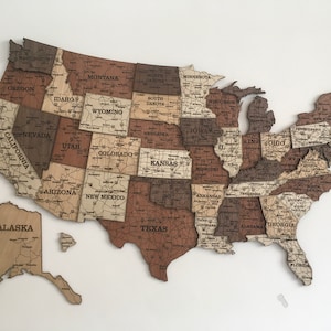 May include: A wooden map of the United States with each state outlined and labelled. The map is made of different shades of brown wood and has a vintage look.