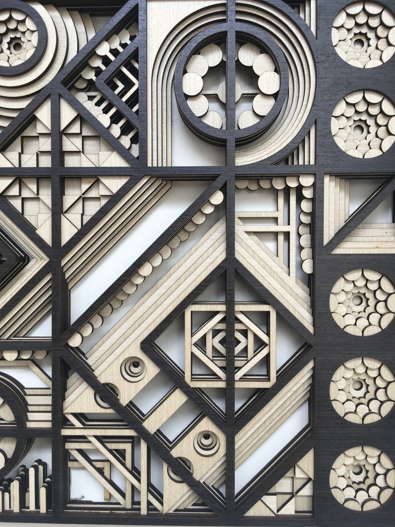 May include: A black and white geometric design with layered circles, squares, and triangles. The design is made of wood and has a 3D effect.