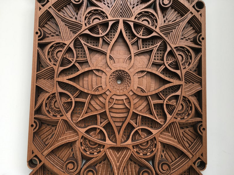 Puede incluir: Una pieza de arte de pared de madera con un intrincado dise&ntilde;o de corte l&aacute;ser que presenta un patr&oacute;n circular de mandala con un centro con forma de flor. El dise&ntilde;o est&aacute; en tonos marrones y tiene un efecto 3D.