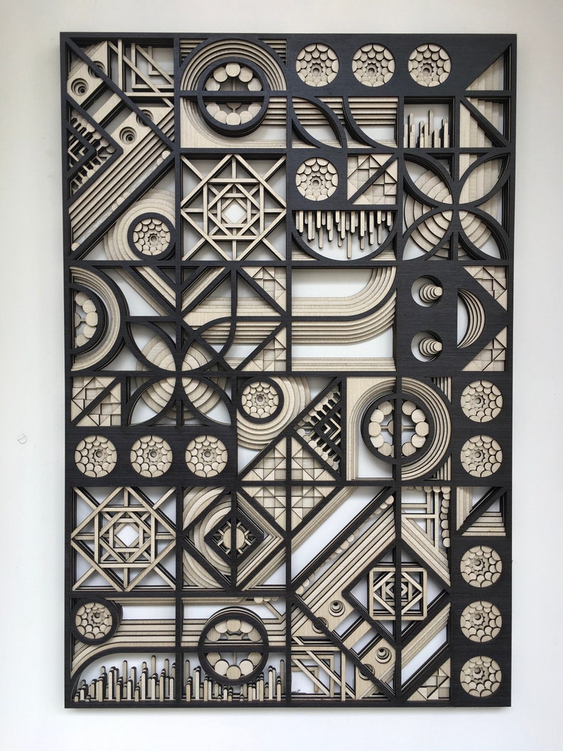 May include: A black and beige geometric wall art piece made of wood. The piece is made up of a variety of shapes, including circles, squares, and triangles. The piece is very detailed and intricate.