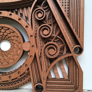 Puede incluir: Una pieza de arte de pared de madera con intrincados dise&ntilde;os cortados con l&aacute;ser. La pieza presenta una variedad de formas geom&eacute;tricas, incluyendo c&iacute;rculos, cuadrados y tri&aacute;ngulos. La madera es de un rico color marr&oacute;n y el dise&ntilde;o es muy detallado.