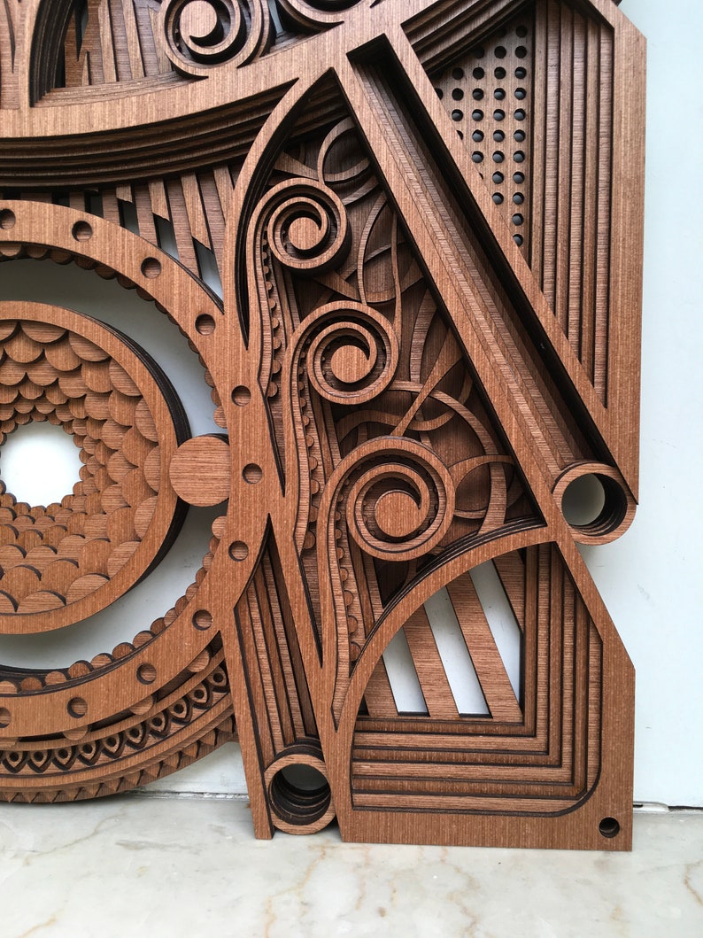 Puede incluir: Una pieza de arte de pared de madera con intrincados dise&ntilde;os cortados con l&aacute;ser. La pieza presenta una variedad de formas geom&eacute;tricas, incluyendo c&iacute;rculos, cuadrados y tri&aacute;ngulos. La madera es de un rico color marr&oacute;n y el dise&ntilde;o es muy detallado.