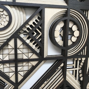 May include: Abstract geometric wall art made of layered wood with a black and white color scheme. The design features circles, squares, and triangles.
