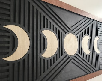 May include: A black wooden wall art piece with a geometric design featuring five crescent moons in a light wood color.