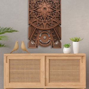 Puede incluir: Una pieza de arte de pared de madera con un dise&ntilde;o geom&eacute;trico en tonos marrones. El arte est&aacute; colgado en una pared gris claro sobre un gabinete de madera con un frente de rat&aacute;n tejido.