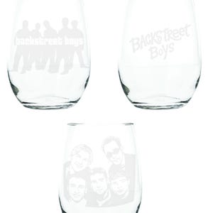 May include: Three clear stemless wine glasses. Two glasses feature the text "Backstreet Boys" and the other glass has a graphic of the band members. The glasses are made of clear glass.