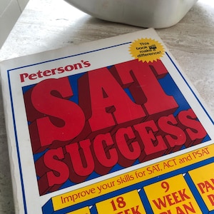 May include: A Peterson's SAT Success study book with a white cover featuring large red block letters. The cover includes yellow text boxes with blue borders detailing an 18 week plan, a 9 week plan, and three ways to get ready for exams.