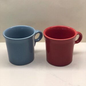 May include: Two ceramic mugs, one blue and one red. The mugs have a simple design and are perfect for everyday use.