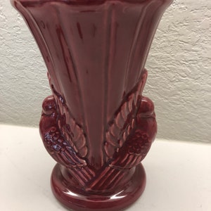 May include: A burgundy ceramic vase with a fluted design and two stylised bird handles.