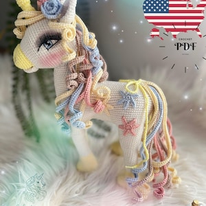 May include: A crocheted unicorn with a cream-colored body, adorned with pastel-colored curls, stars, and flowers. The unicorn has blue eyes, pink cheeks, and a yellow horn. The image includes the text "CROCHET PDF PATTERN".