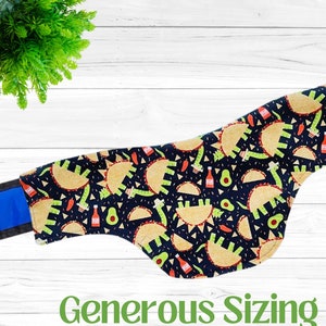 May include: A black fabric dog collar with a blue trim and a colorful print of tacos, avocados, and hot sauce. The collar has the text "Generous Sizing" printed on the bottom.