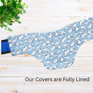 May include: A light blue and white shark-patterned saddle pad with blue and black accents. The saddle pad is fully lined and features a repeating pattern of sharks. The text "Our Covers are Fully Lined" is visible.