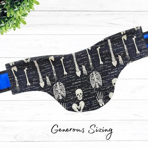 May include: Black bandana with a white skeleton print. The print features bones, skulls, and a diagram of the human body. The bandana has a blue trim and the text "Generous Sizing" is printed below the bandana.