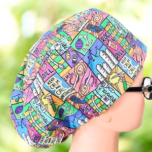 May include: A colorful surgical scrub hat with a variety of medical-themed illustrations and text, including "Keep Calm and Call Anesthesia", "ROC & Roll", and "O₂ To Go".