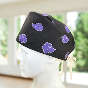 May include: Black surgical scrub cap with a repeating pattern of purple clouds. The cap is tied in the back with cream-colored ties. The clouds have a white outline and a dotted purple interior.