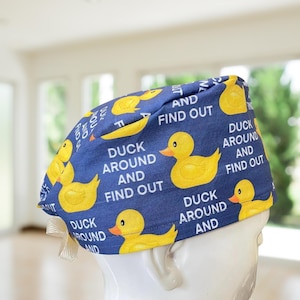 May include: Blue scrub hat with a pattern of yellow rubber ducks and the text "Duck Around and Find Out".