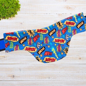 May include: Blue fabric with a pattern of colorful comic book words like "Super!" and "Zap!" on a white background.