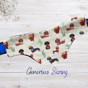 May include: A dog bandana with a repeating pattern of dachshunds wearing cowboy hats and bandanas, along with green cacti. The text "Generous Sizing" is written in cursive. The bandana has a blue strap.