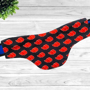 May include: A black fabric bandana with a red cloud pattern. The bandana has a blue trim around the edges.