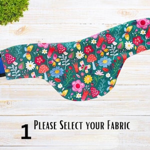 May include: A green fabric with a colorful floral and mushroom pattern. The fabric is folded into a curved shape. The text "1 PLEASE SELECT YOUR FABRIC" is visible at the bottom of the image.