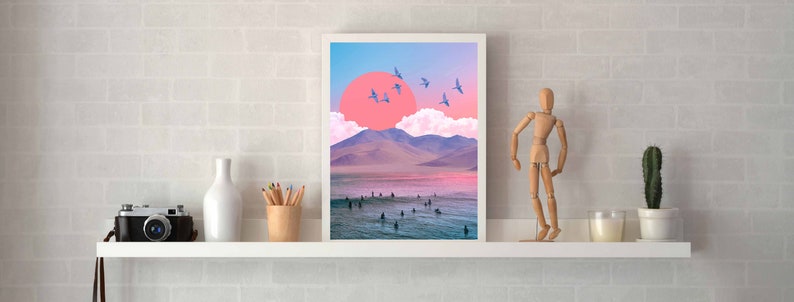 May include: A framed print of a digital collage featuring a pink sunset over a mountain range with a flock of blue birds flying overhead. The scene is set against a blue sky with white clouds.