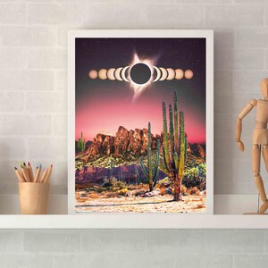 May include: A framed print of a desert landscape with a sunset sky and a solar eclipse. The eclipse is shown in stages, with the moon passing in front of the sun. The desert scene features tall cacti and rocky mountains.