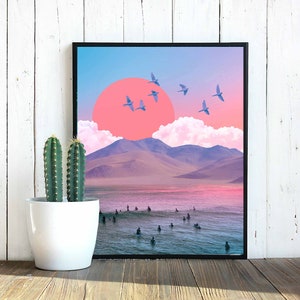May include: A framed digital collage featuring a pink sunset over a mountain range with a blue ocean and surfers in the foreground.  The sky is a gradient of blue, pink, and purple with white clouds.  There are several blue birds flying in the sky.
