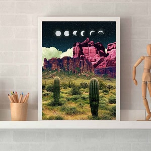 May include: A framed print of a desert landscape with a pink mountain range and cacti in the foreground. The sky is dark blue with white and gray moons in various phases.