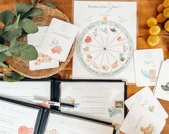 May include: A set of 12 colorful cards with illustrations and numbers representing the months of the year. The cards are arranged in a basket and on a wooden table. The cards are part of a learning activity for children.