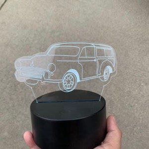May include: A white outline of a vintage car is etched into a clear acrylic night light. The night light is sitting on a black base.