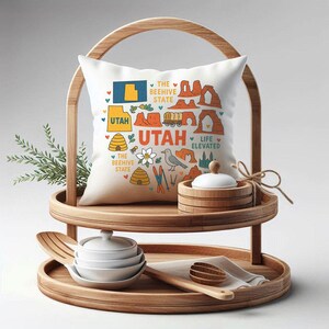May include: A decorative pillow with a Utah-themed design, featuring illustrations of the state's landmarks and the text "Utah". The pillow is displayed on a wooden tiered serving tray, alongside serving bowls and utensils. The tray has a natural wood finish.