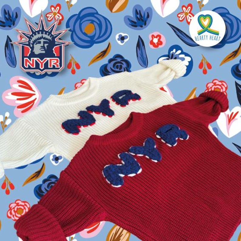 May include: Two long-sleeved knit sweaters, one white and one dark red, each featuring the letters NYR in dark blue textured applique on the chest. The sweaters have a ribbed texture and crew necklines, displayed against a blue floral background.